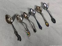 Six sterling souvenir spoons laid out