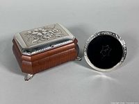 Wooden footed jewelry box beside round sterling picture frame