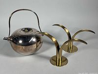 Dansk silver-plated teapot with handle up, two brass lily candlesticks