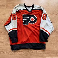 Full front view of jersey displaying team logo and sleeve numbers