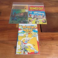 Group shot of all three sleeved comics: Forbidden Knowledge, Flamed-Out Funnies No.2, Dutch Treat