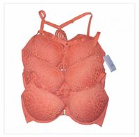 Stacked view of three identical coral lace racerback bras showing front lace detail and tags