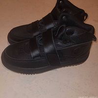 Side view of both sneakers showing high-top profile, straps, and outsole
