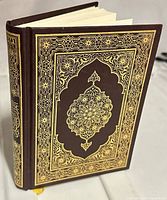 Front and spine of brown hardcover Quran with gold decorative design