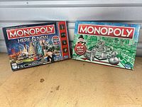Both Monopoly board game boxes displayed side by side on tabletop