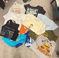 All eleven graphic tees arranged on floor