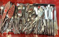 Top view of entire assortment of flatware and serving pieces in red bin