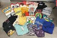 All 25 assorted graphic tees laid out on floor