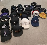 All 26 baseball and trucker hats laid out on floor showing fronts