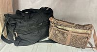 Front view of both LeSportsac bags, black duffel left, leopard print crossbody right