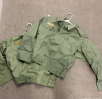 Two olive green military shirts on hangers