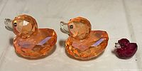 Two large peach crystal ducks and one small red crystal duck
