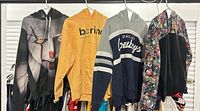 Front view of four assorted hoodies hanging