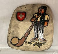 Front view of the ceramic plaque showing alphorn player and Swiss flag design