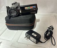 Camcorder on carrying case with charger alongside