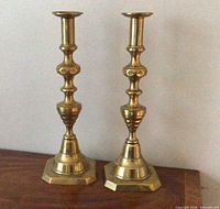 Full view of both brass candlesticks standing on surface