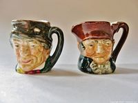 Front view showing both miniature jugs with styled faces and handles