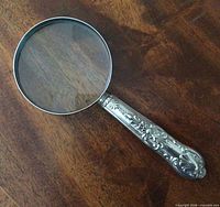 Full view of magnifying glass showing sterling handle and glass lens