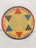 Front view of round tin Chinese Checkers board showing graphics and perforations