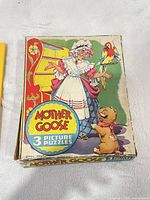 Box lid showing Mother Goose artwork and title indicating 3 picture puzzles