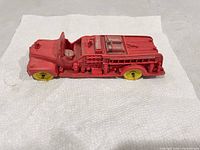 Top and left side view of red rubber firetruck showing overall form, hose reels, pump details, yellow wheels