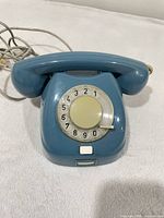 Front view of blue rotary telephone showing dial and handset