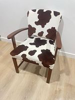Front view of armchair showing cowhide print upholstery and wooden frame