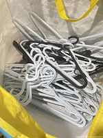 White woven tote holding mix of white and black plastic hangers