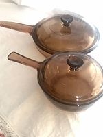 Pair of amber glass Corning Ware saucepans with lids