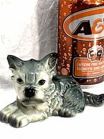 Full view of grey and white porcelain puppy figurine next to a soda can for scale
