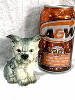 Front view of porcelain terrier figurine beside soda can for scale
