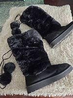 Full view of both boots showing exterior faux fur, suede vamps, drawstrings and pom-poms