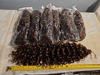 Six sealed extension bundles and one loose bundle displayed with measuring tape