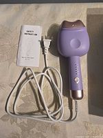 Curling iron with cord and instruction manual displayed