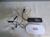 Overview of all items: USB-C hub, battery pack, two white wired earbuds, black neckband earbuds