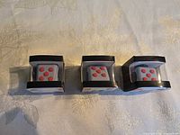 Front view of three boxed grey fidget cubes with red buttons