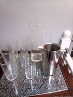 overall view of glass pitcher, stainless steel pitcher, and four glasses on table