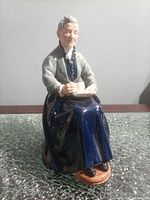 Front view of figurine showing elderly woman holding cup