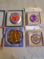 Overview of four boxed compact mirror purse hooks