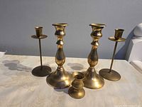Front view of five brass candlesticks showing styles and finish
