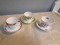 Three teacup and saucer sets displayed upright