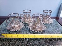 four glass tea cups in metal holders, ruler for scale