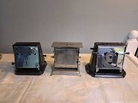 Front view of three vintage toasters showing chrome panels and overall condition