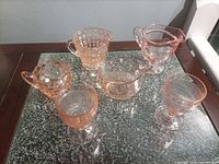 Six pink/peach glass pieces displayed on table