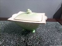 Trinket box with lid on showing green iridescent body, white lid, gold trim, four feet