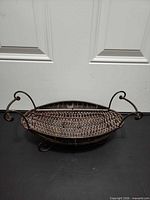 Top view showing oval woven metal tray, twisted handles, scrolled feet