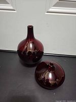 Both burgundy glass vases, showing relative sizes and shapes