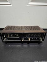 Front view showing flip clock display, radio dial, knobs, and wood-grain cabinet