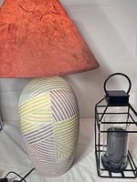 Ceramic lamp with shade beside metal lantern