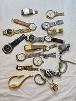Full overview of 24 assorted wristwatches and loose links spread on white background